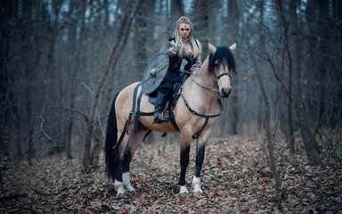 Viking warrior female ridding a horse at twilight autumn forest - Medieval movie scene