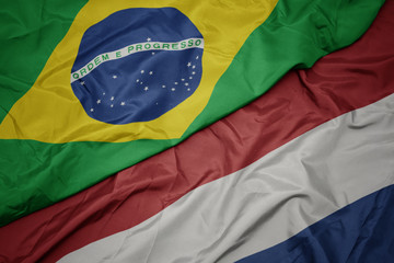 waving colorful flag of netherlands and national flag of brazil.