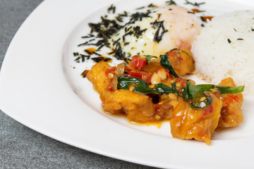 Fried fish in spicy and oyster sauce with onsen egg in white plate on tile table.