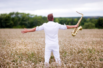 saxophonist in a white suit stands in the field. Flight of the soul, philosophy of freedom