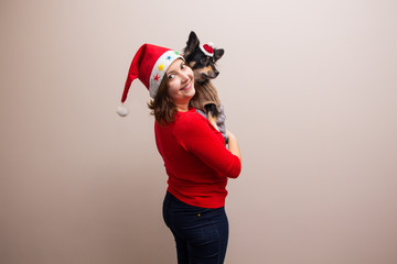 Happy girl in santa hat in red blouse with little black dog