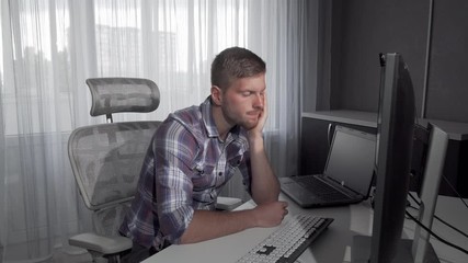Handsome man falling asleep in front of his computer. Attractive male student looking tired after studying. Computer programmer falling asleep after night of working 4k footage