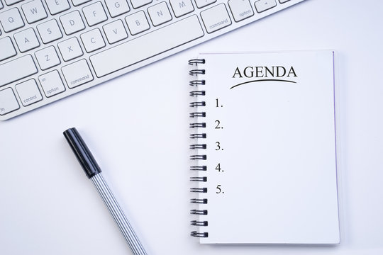 Business agenda, planning concept. Spiral notebook with Agenda text on white background. Flat lay or top view.