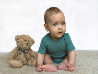Sweet little baby boy with teddy bear on white background