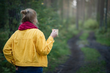 Woman hiker meets cold morning with a cup of hot coffee.