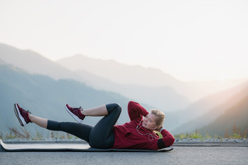 Adult fit woman exercising at the top of the mountain.