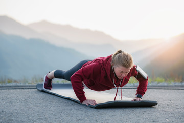 Fit female doing intense core workout. Adult woman doing push up exercise on fitness mat.