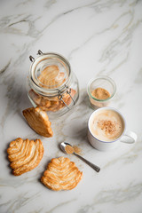 Italienische Blätterteig Fächer Kekse mit Einmachglas und Becher Kaffee auf Marmor Hintergrund