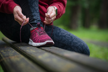 Tying sports shoe. Female athlete getting ready for athletic and fitness training outdoors.