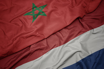 waving colorful flag of netherlands and national flag of morocco.