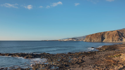 Volcanic rocky landscape of Malpais de la Rasca, a natural reserve close to Palm-Mar town, with views towards Atlantic Ocean and the tourist resort Los Cristianos, in Tenerife, Canary Islands, Spain 