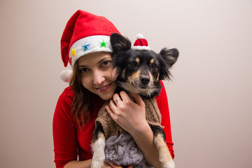 Happy girl in santa hat in red blouse with little black dog