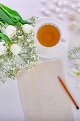 Teacher's Day, March 8th, International Women's Day, mother's day, valentine's day. Cup of tea, bouquet of tulips and sweets on the white table. Pencil and blank paper for drawing or writing
