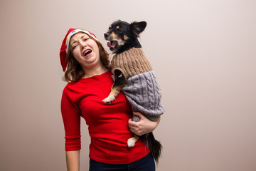 Happy girl in santa hat in red blouse with little black dog