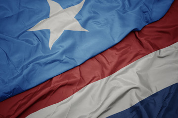 waving colorful flag of netherlands and national flag of somalia.