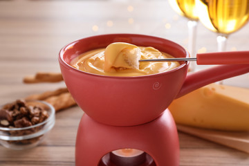 Pot with delicious cheese fondue and bread on table, closeup