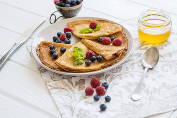  breakfast pancakes with blueberries raspberries and honey on a white table tea with lemon and cinnamon