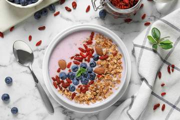 Flat lay composition of smoothie bowl with goji berries on marble table