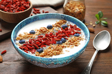 Smoothie bowl with goji berries and spoon on wooden table