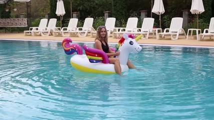 Woman swimming on inflatable unicorn in pool
