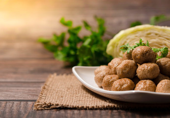 Stack of baked meatballs in white dish on wodden background, copy space.