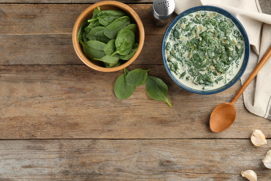 Tasty spinach dip on wooden table, flat lay. Space for text