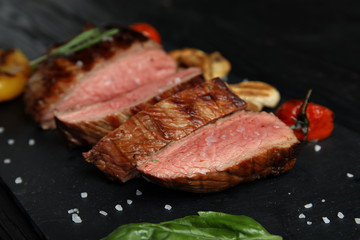 Grilled meat served with garnish on slate plate, closeup