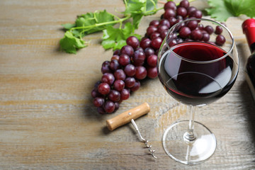 Fresh ripe juicy grapes and glass of wine on wooden table