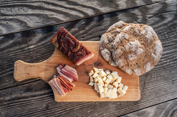 Snack with delicious South Tyrolean smoked bacon and cheese with flat bread lying on a rustic table
