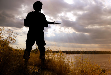 Fototapeta premium Soldier with machine gun patrolling outdoors. Military service