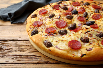 pizza con cipolla salame e olive sfondo rustico