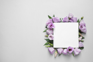 Flat lay composition with beautiful Eustoma flowers and card on grey background, space for text