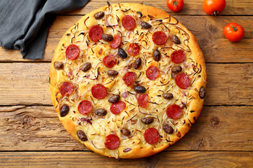 pizza con cipolla salame e olive sfondo rustico