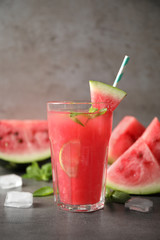 Glass of tasty refreshing drink with watermelon on grey table