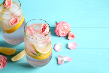 Obraz na płótnie Canvas Tasty refreshing lemon drink with roses on light blue wooden