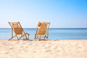 Wooden deck chairs on sandy beach near sea