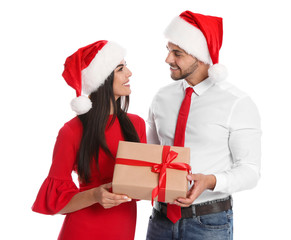 Lovely young couple in Santa hats with gift box on white background. Christmas celebration