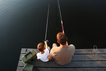 Dad and son fishing together at lake, above view