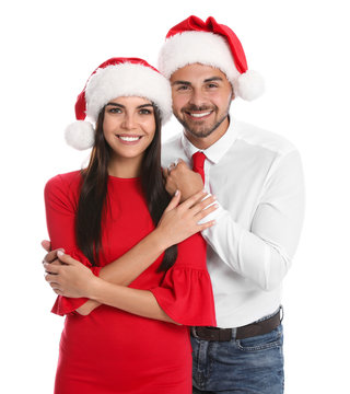 Lovely young couple in Santa hats on white background. Christmas celebration