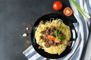 1 plate of Italian meat paste with tomato and celery on towel and black background, spices, top view