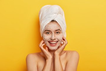 Pleasant looking happy woman unclogges pores, makes beauty step to improve skin, wears nourishing...