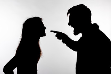 Aggression and abuse concept - man and woman expressing domestic violence in studio silhouette isolated on white background.