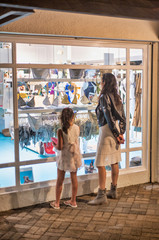 Night view of woman with daughter watching shop showcase