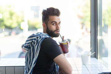 Portrait of a handsome arab man drinking smoothie in a cafe. The concept of rest and break