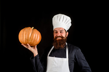 Healthy organic harvest vegetables. Bearded cook in chef uniform with pumpkin. Autumn food concept. Chef man in white apron presenting pumpkin for culinary. Thanksgiving seasonal cooking ingredients.