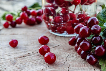 Jar with an elixir or tincture with viburnum berries on a wooden background, a red twig of viburnum in the background.