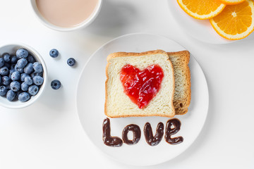 two fresh toast with heart of jam on the white table, orange