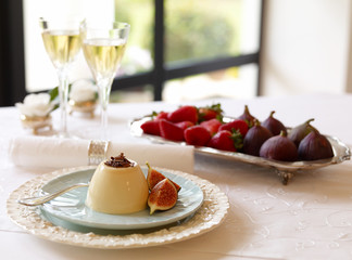 Fig mousse Dessert on table setting with window, figs, strawberries and wine in glass