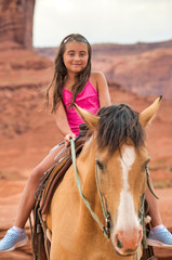 Fototapeta premium Happy young girl riding horse in Monument Valley