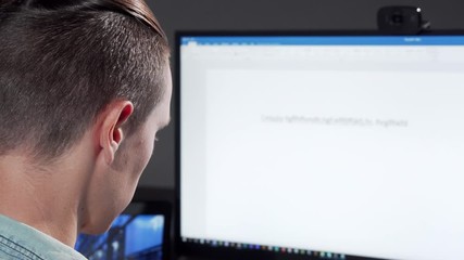 Rear view cropped shot of a computer programmer working late in IT office. Unrecognizable man working on a computer late at night, copy space. Programming concept